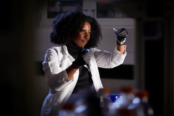 A scientist holding a vial up to the light